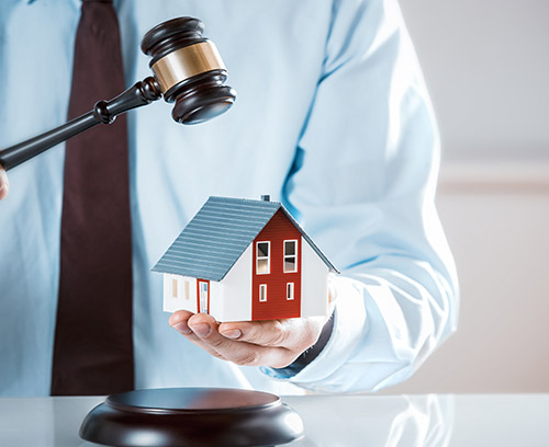a gavel hitting a small house toy